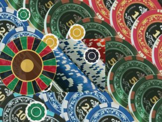 Colorful casino chips surround a roulette wheel, depicting gambling.