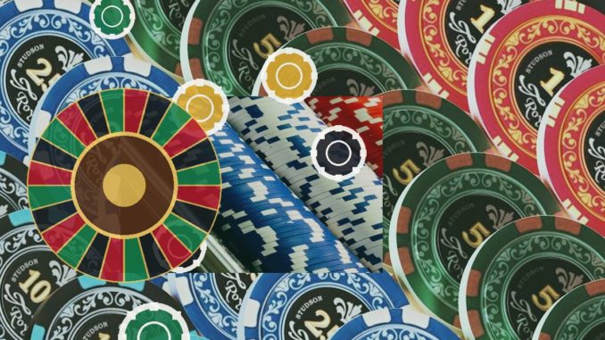 Colorful casino chips surround a roulette wheel, depicting gambling.